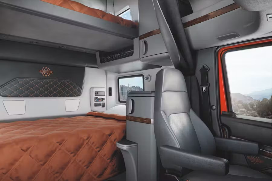 The view inside a bunk of a International semi truck showing a seat and two beds.