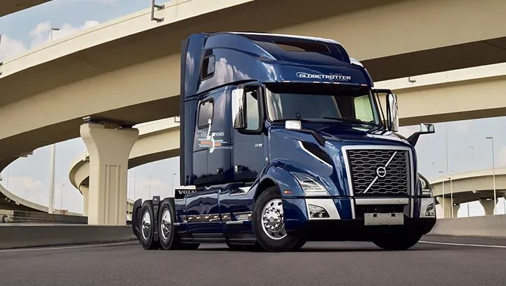 Right side view of a dark blue Volvo vnl 760 semi truck parked under a overpass.